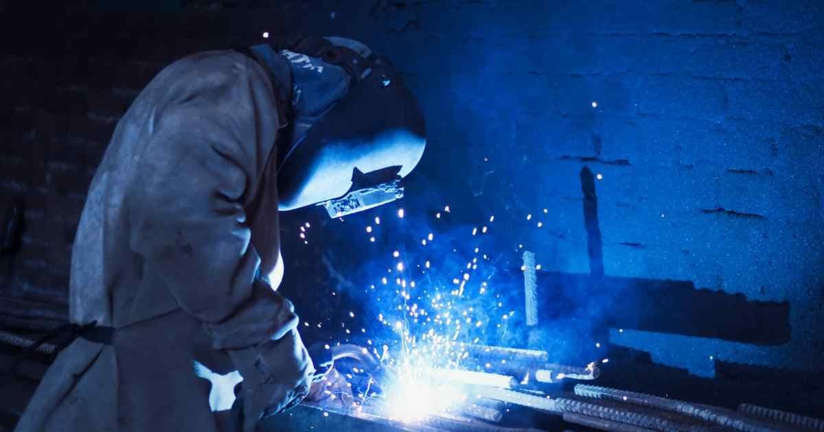Experienced welder performing MIG welding on steel components in an industrial workshop