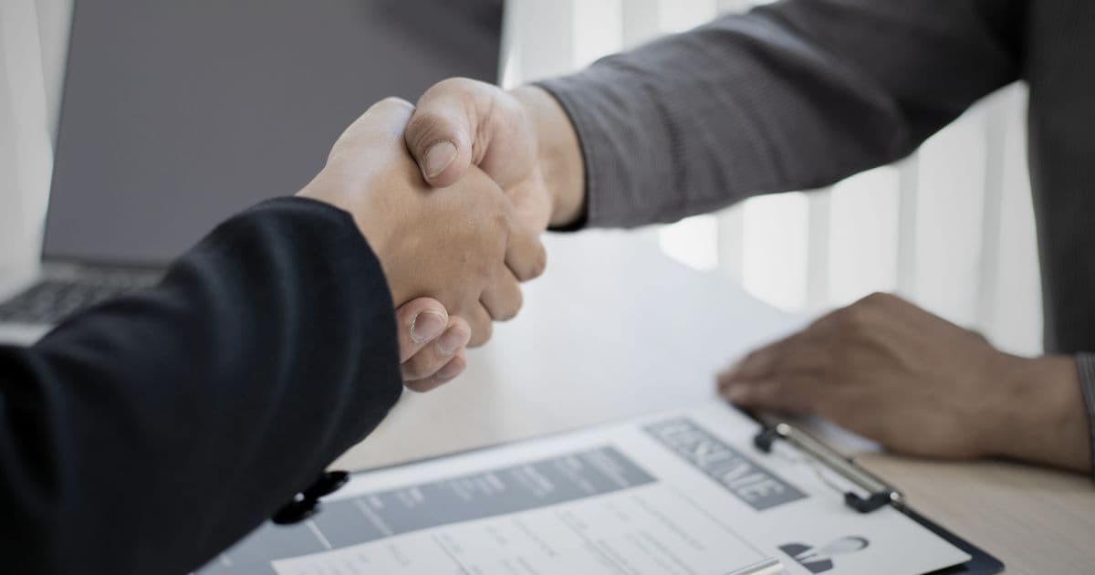 handshake-between-job-applicant-hiring-manager-with-single-page-resume-on-desk-for-perfect-resume-length