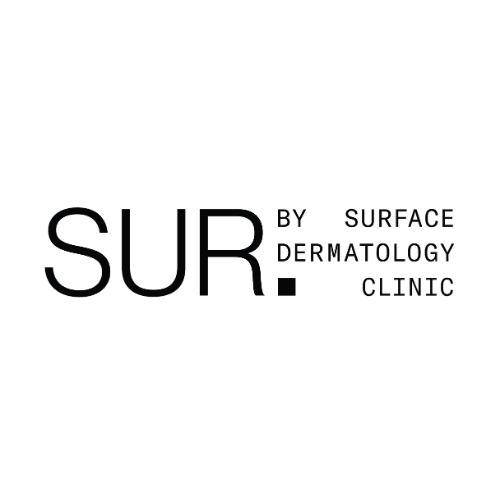 Two clinic team members reviewing patient feedback together at the front desk of a dermatology clinic, smiling at a tablet screen
