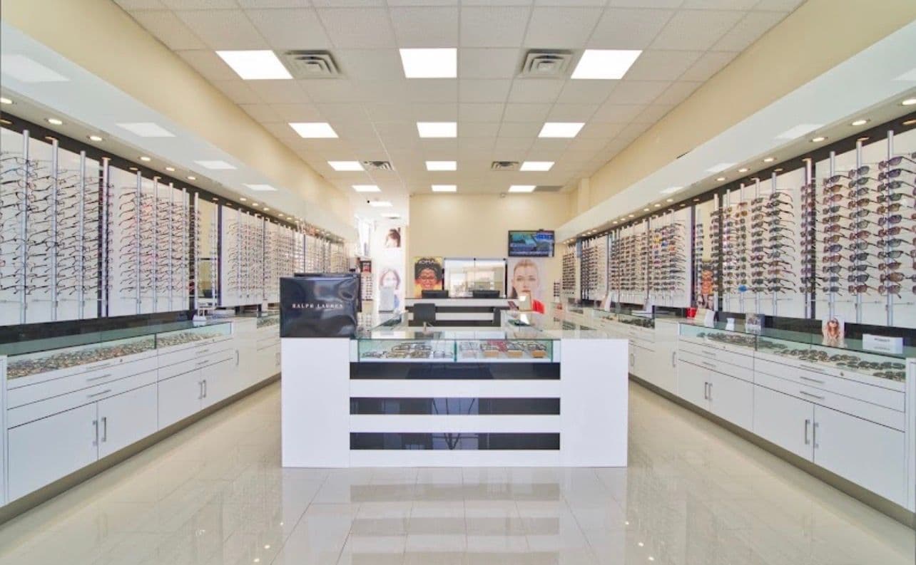 Optical clinic team reviewing patient feedback and Google reviews together at the front desk, with eyewear frames visible in the background