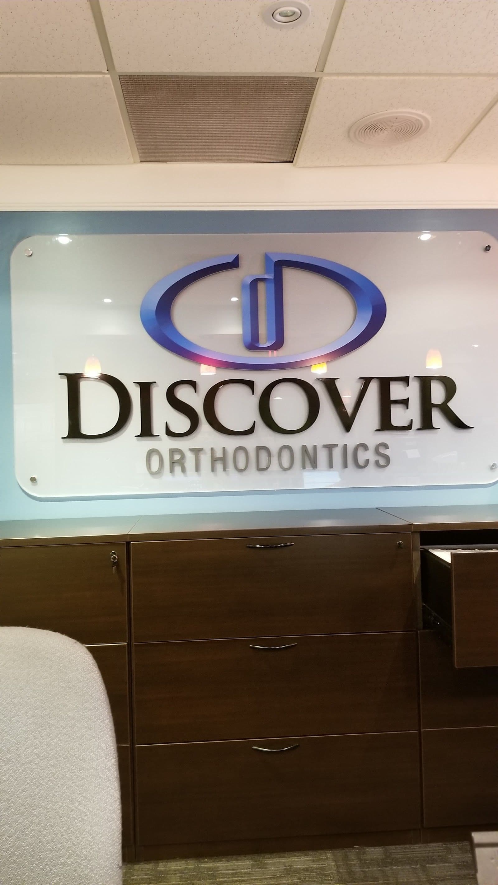 Orthodontic practice manager and front desk lead reviewing patient feedback together on a tablet at the reception desk of Discover Orthodontics