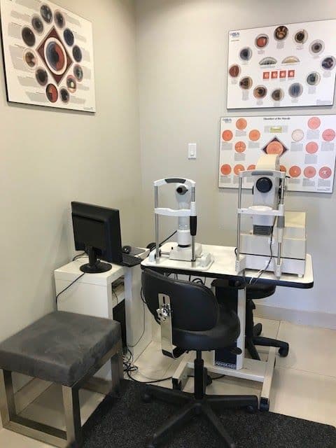 Optometry clinic team reviewing patient feedback together at the front desk, with a computer screen displaying Google reviews