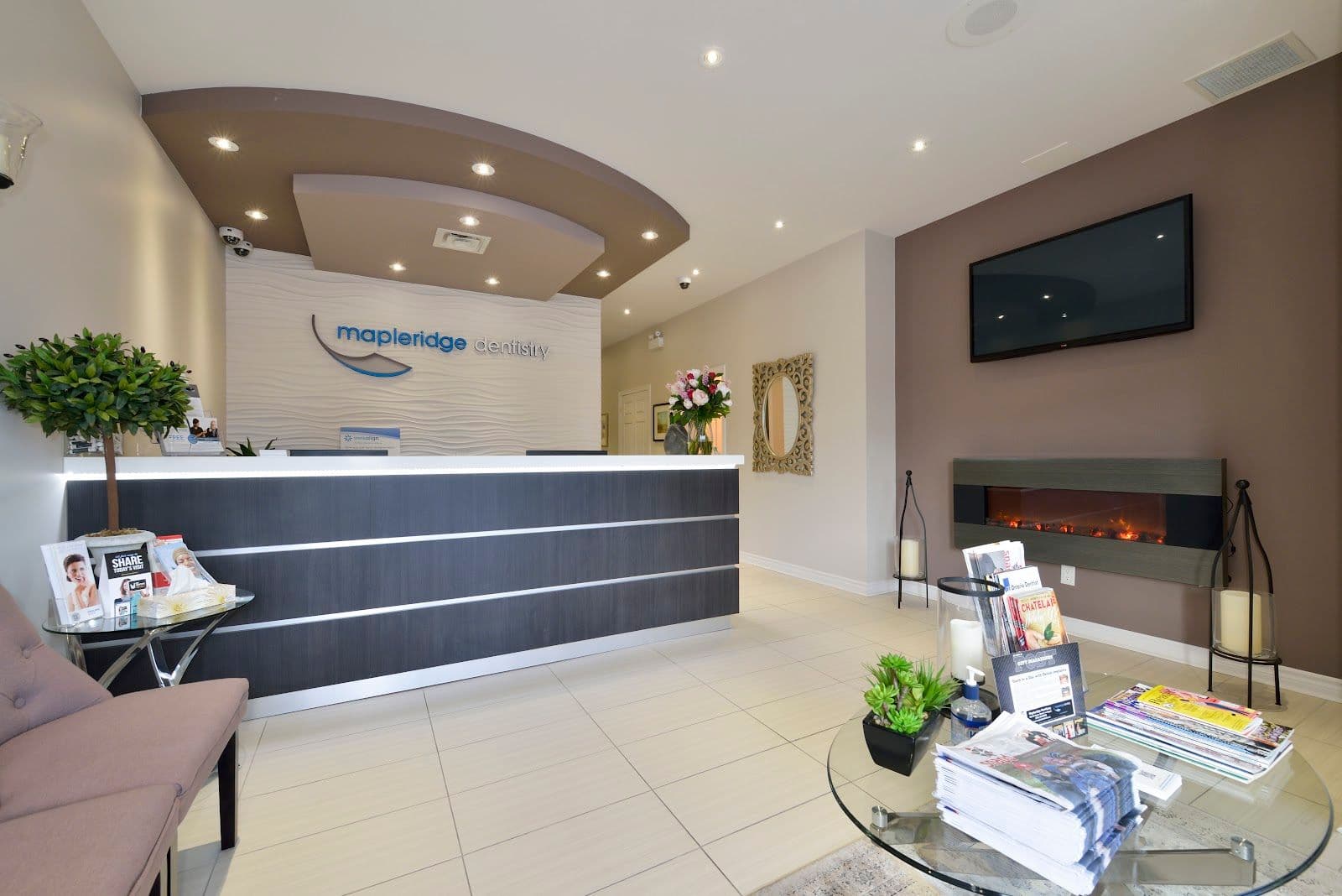 A dental clinic front desk team reviewing patient feedback together on a tablet, smiling in a bright and welcoming reception area