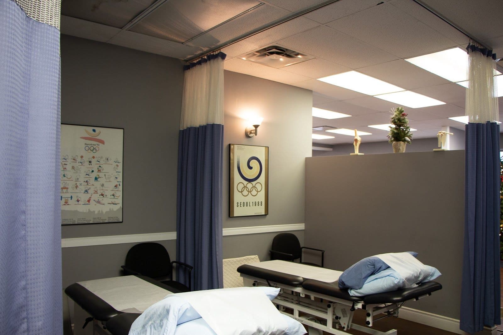 A physiotherapy clinic team member reviewing patient feedback on a tablet at the front desk of a clean, well-equipped treatment area