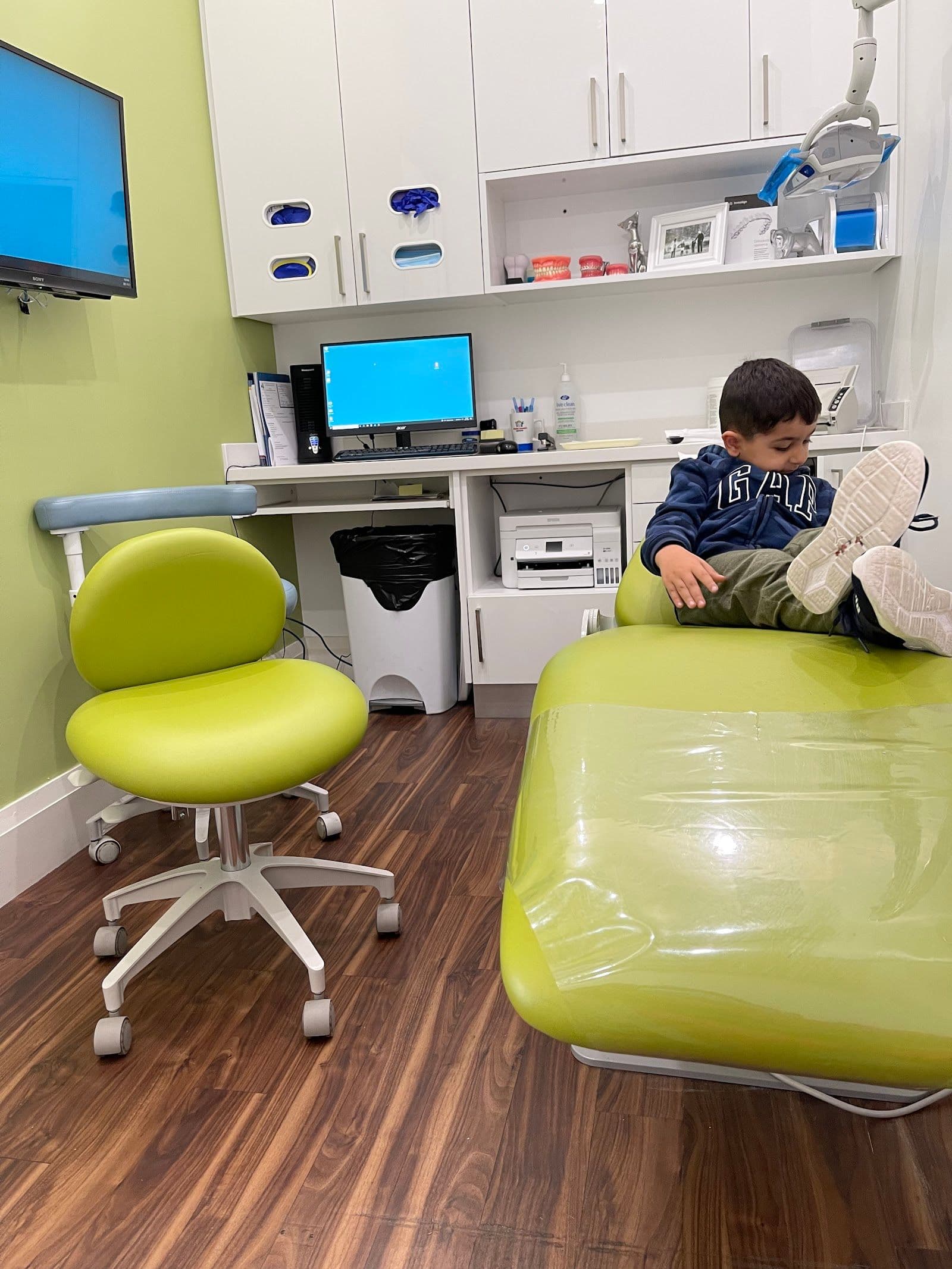 A dental clinic team member and front desk coordinator reviewing patient feedback on a tablet near the reception desk of a pediatric dental office