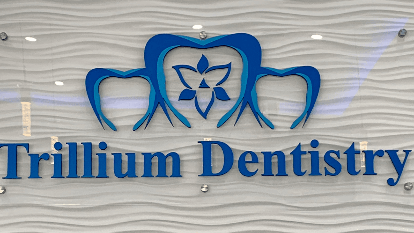 Dental clinic front desk team reviewing patient feedback together on a tablet in a clean, modern reception area