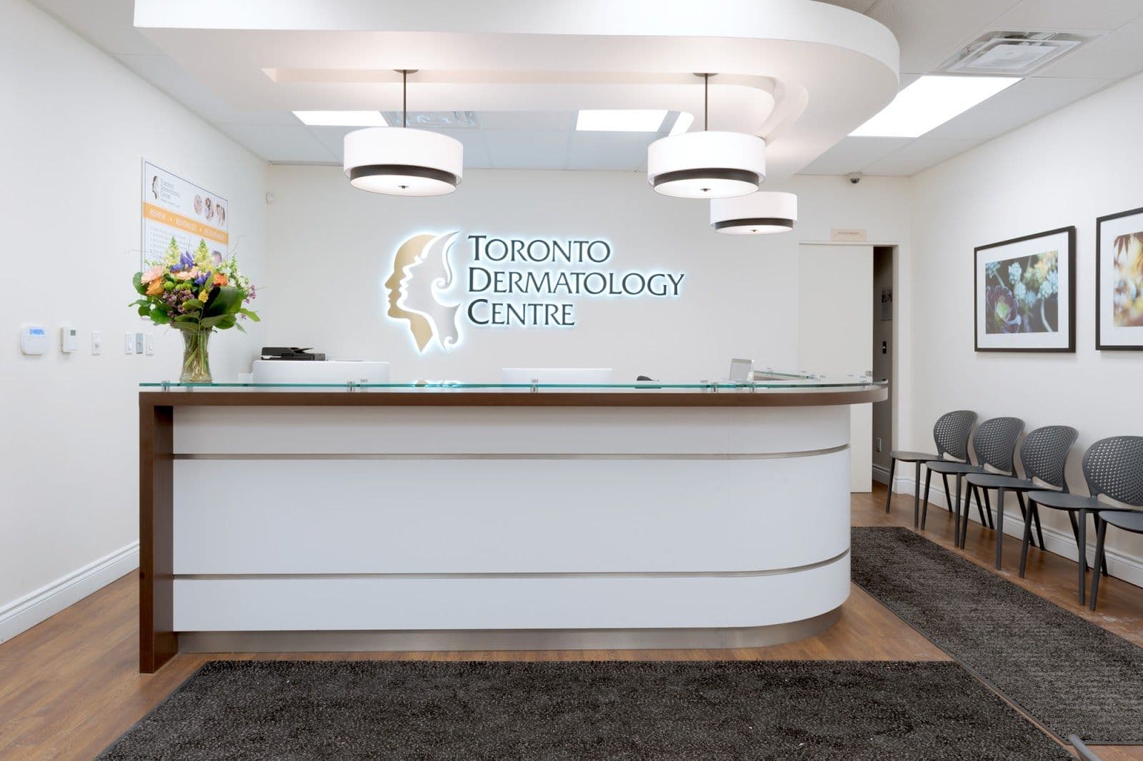 Dermatology clinic front desk team reviewing patient feedback together on a tablet in a bright, modern reception area