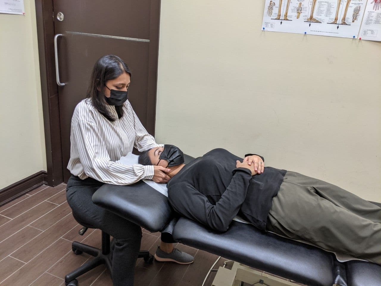 Physiotherapy clinic team reviewing patient feedback on a tablet at the front desk of a bright, welcoming treatment centre