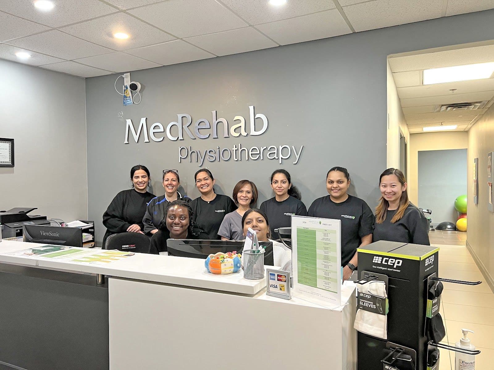 MedRehab Group clinic staff reviewing patient feedback together at the front desk, with a tablet displaying Google review summaries