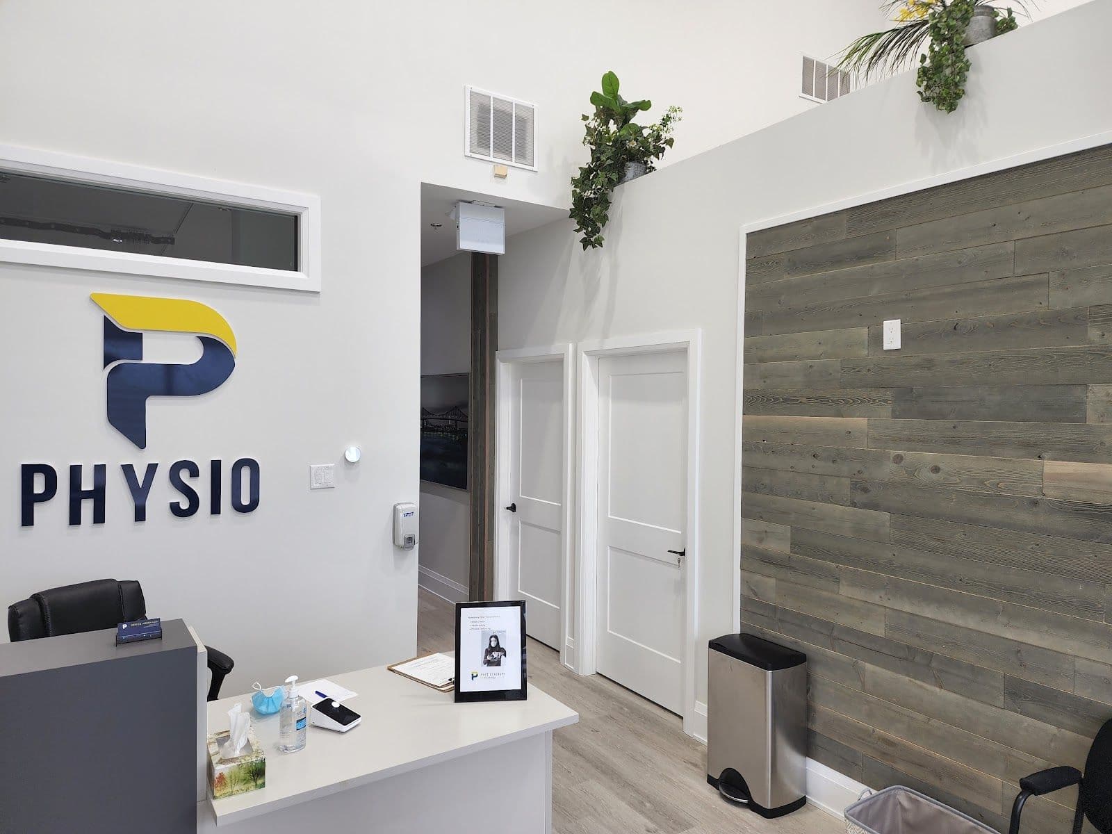 A physiotherapy clinic front desk team reviewing patient feedback together on a tablet in a clean, welcoming treatment area