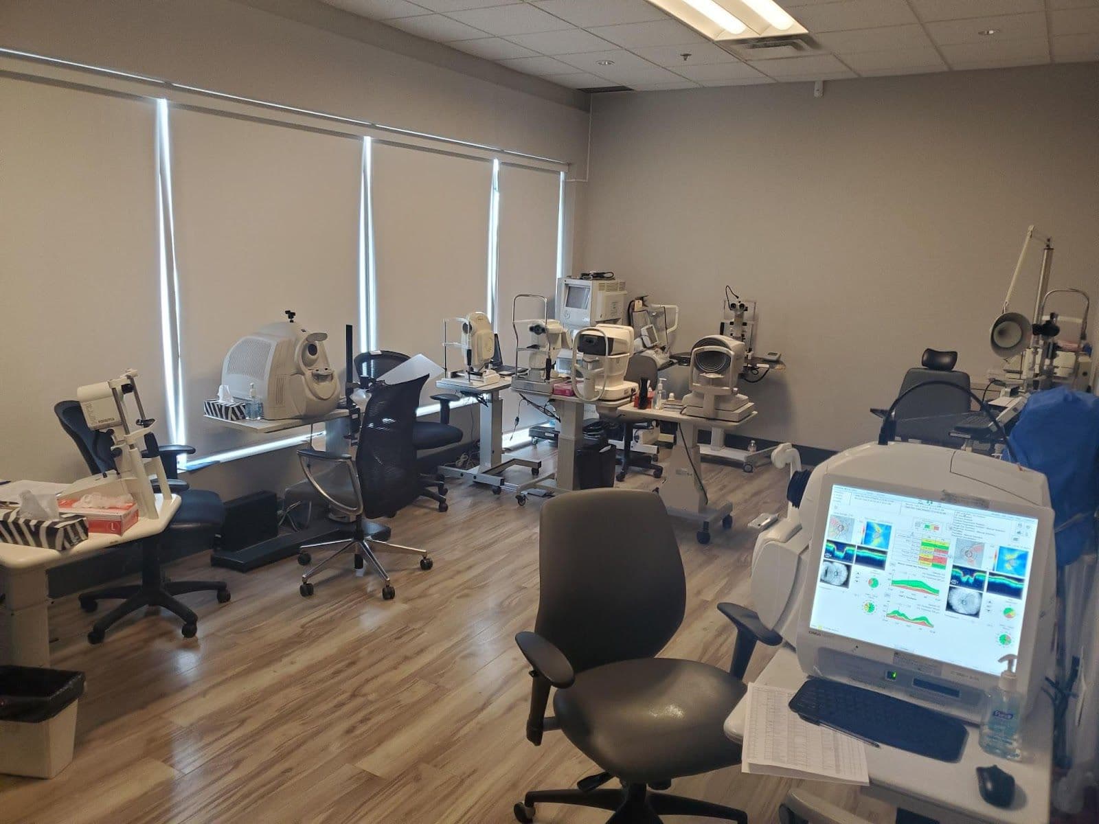 An optometry clinic team reviewing patient feedback together at the front desk, with a monitor showing Google review summaries