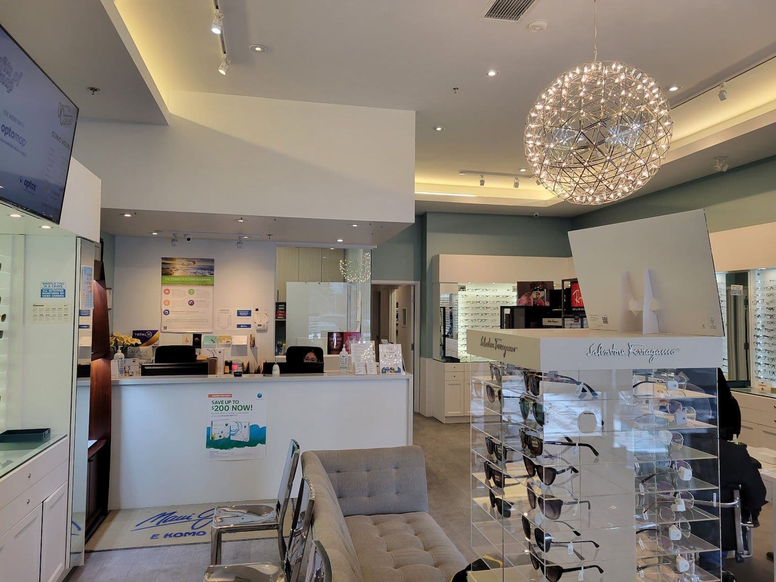 Optometry clinic team reviewing patient feedback together at the front desk, with an optical display in the background