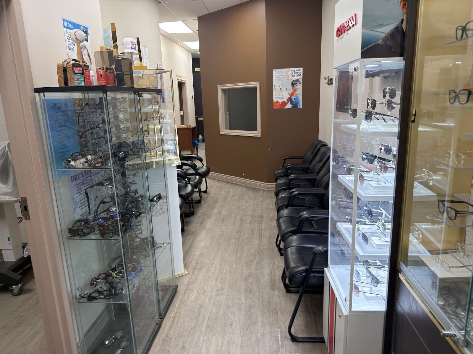 Optometry clinic team reviewing patient feedback together at the front desk, with frames and an eye exam chart visible in the background