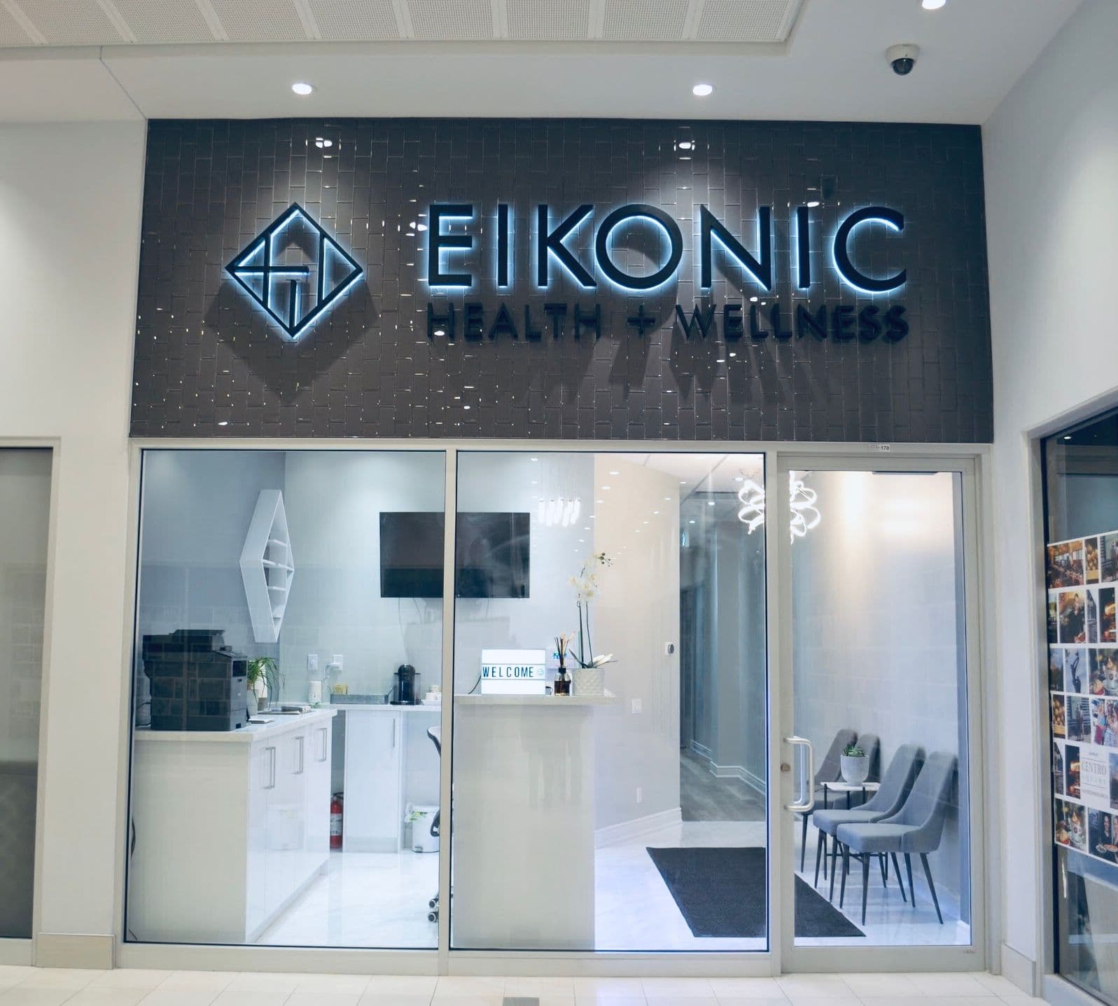 A clinic team member and practitioner reviewing patient feedback together at the front desk of a modern chiropractic and wellness clinic