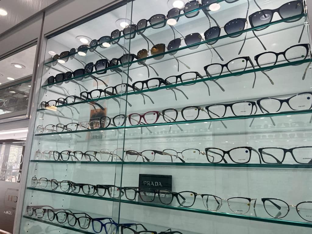 Optometry clinic team reviewing patient feedback together at the front desk, with an eyewear display visible in the background