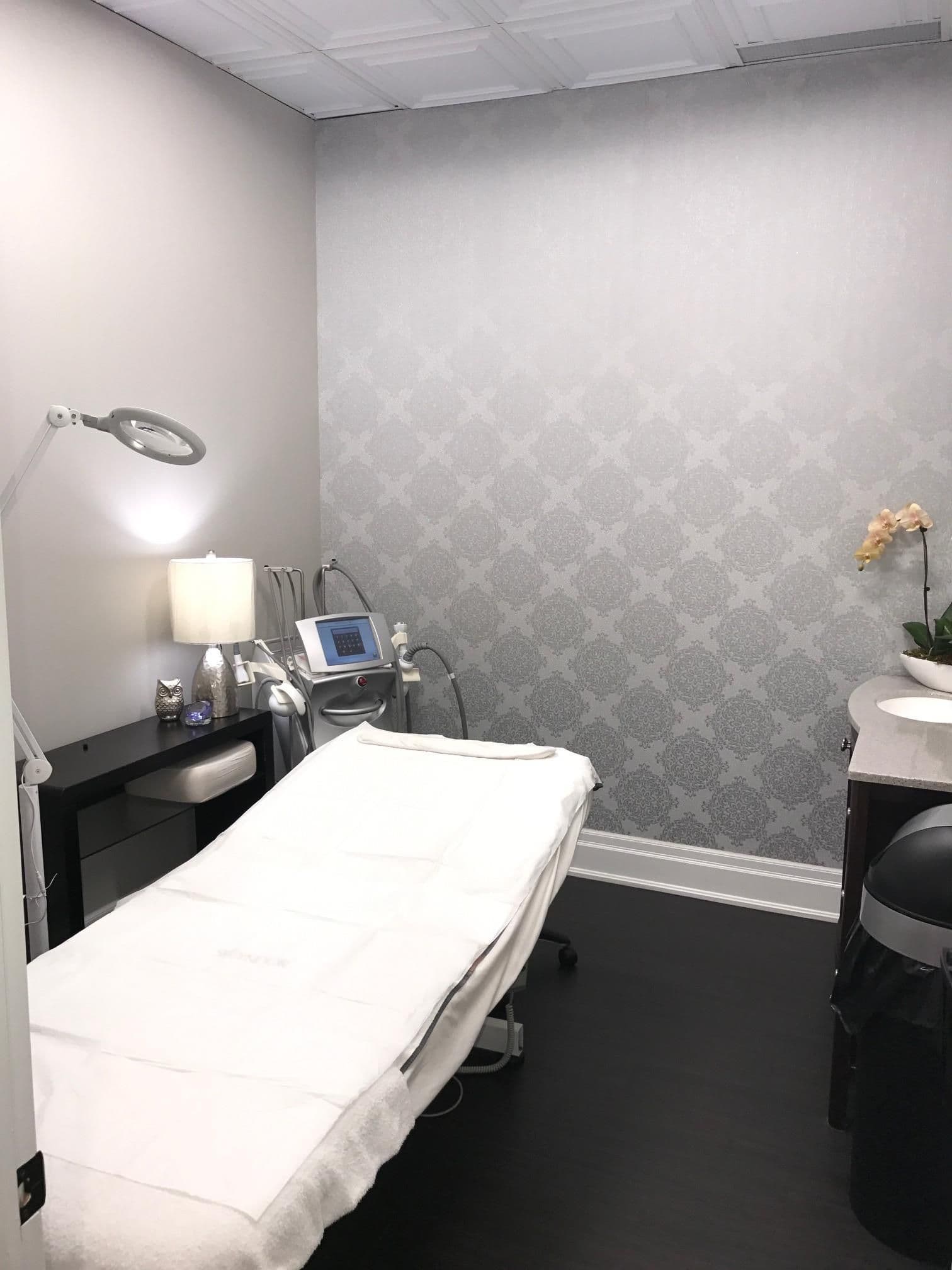 A clinic team member and front desk lead reviewing patient feedback and Google review highlights together on a tablet in a clean medical spa treatment area