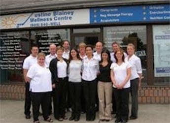 Chiropractic clinic front desk team reviewing patient feedback together on a tablet in a bright, welcoming reception area