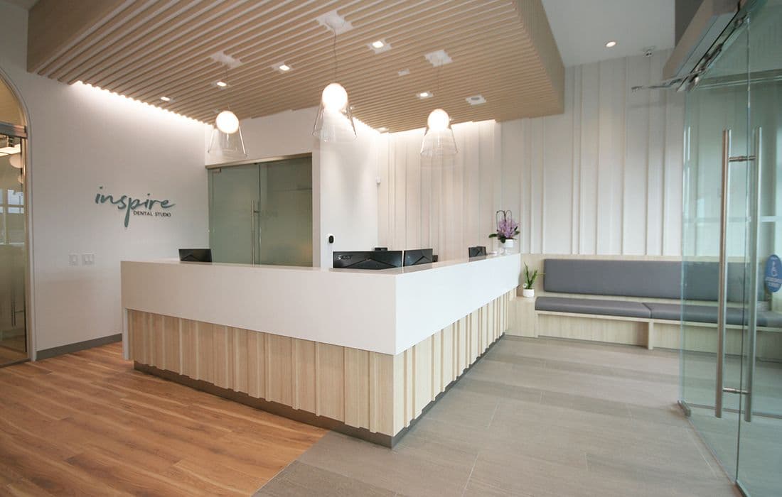 Dental clinic front desk team reviewing patient feedback together on a tablet in a bright, modern reception area at Inspire Dental Studio