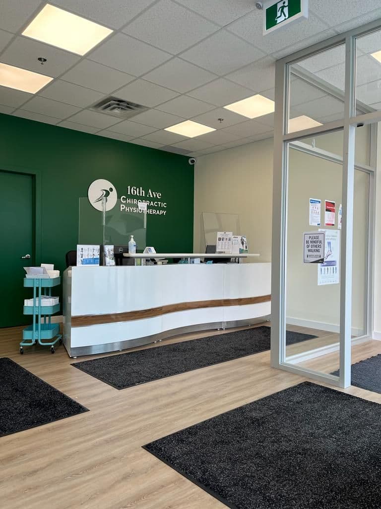 Clinic team at the front desk reviewing patient feedback and Google reviews together on a tablet at 16th Ave Chiropractic and Physiotherapy