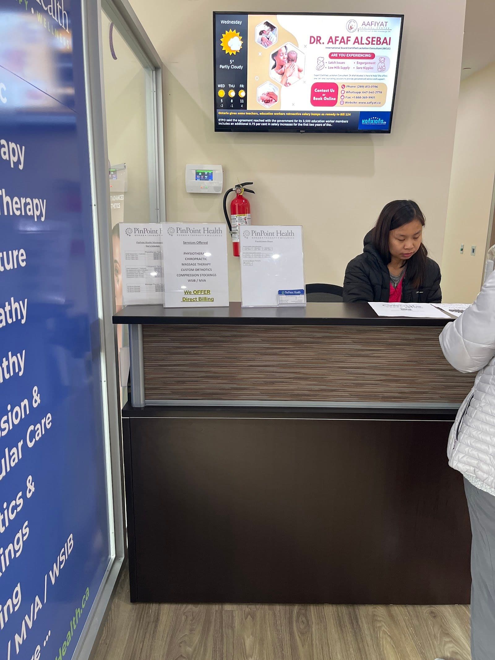 A clinic coordinator and physiotherapist reviewing patient feedback together at the front desk of a rehabilitation clinic in Mississauga