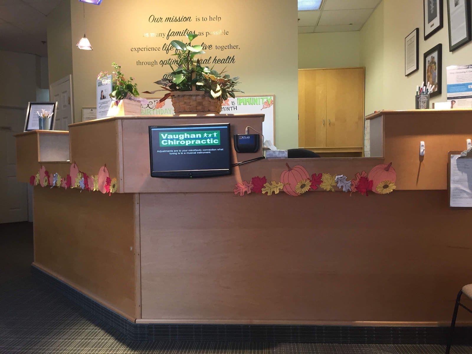 Chiropractic clinic front desk team reviewing patient feedback and Google reviews together on a tablet in the reception area