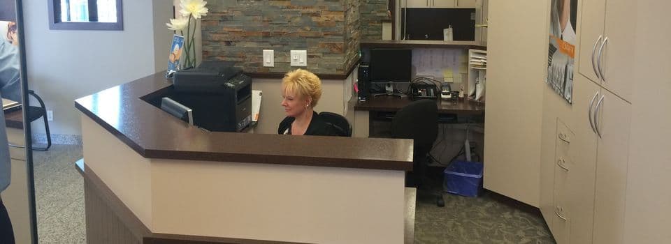 An optometry clinic team member reviewing patient feedback on a tablet at the front desk of an eye care practice