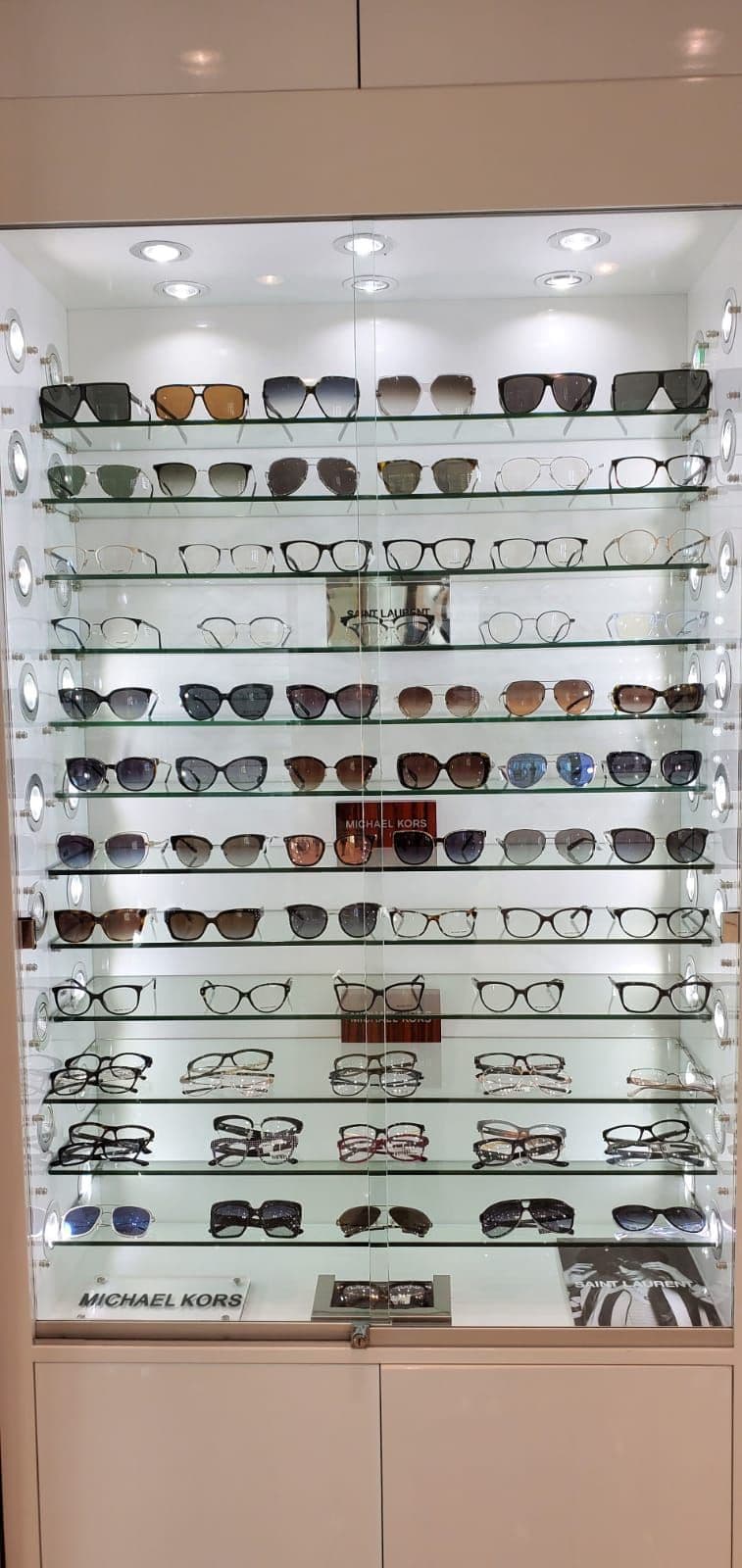 Optometry clinic team reviewing patient feedback together at the front desk, with eyeglass frames displayed in the background