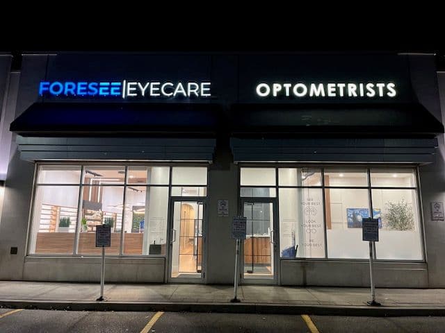 Optometry clinic front desk team reviewing patient feedback together on a tablet in a bright, modern reception area