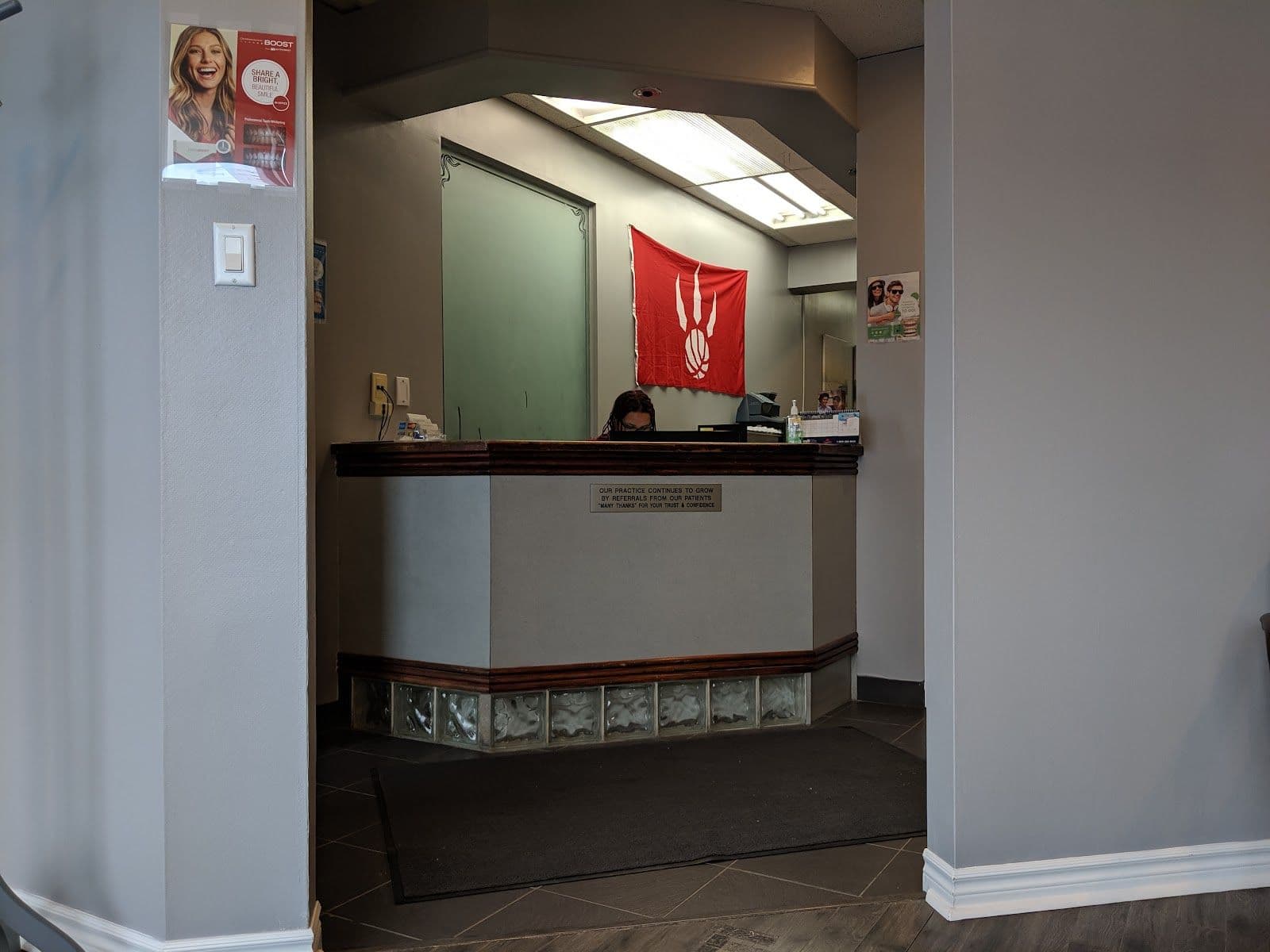 A dental clinic front desk team reviewing patient feedback together on a tablet, with a bright and welcoming reception area in the background