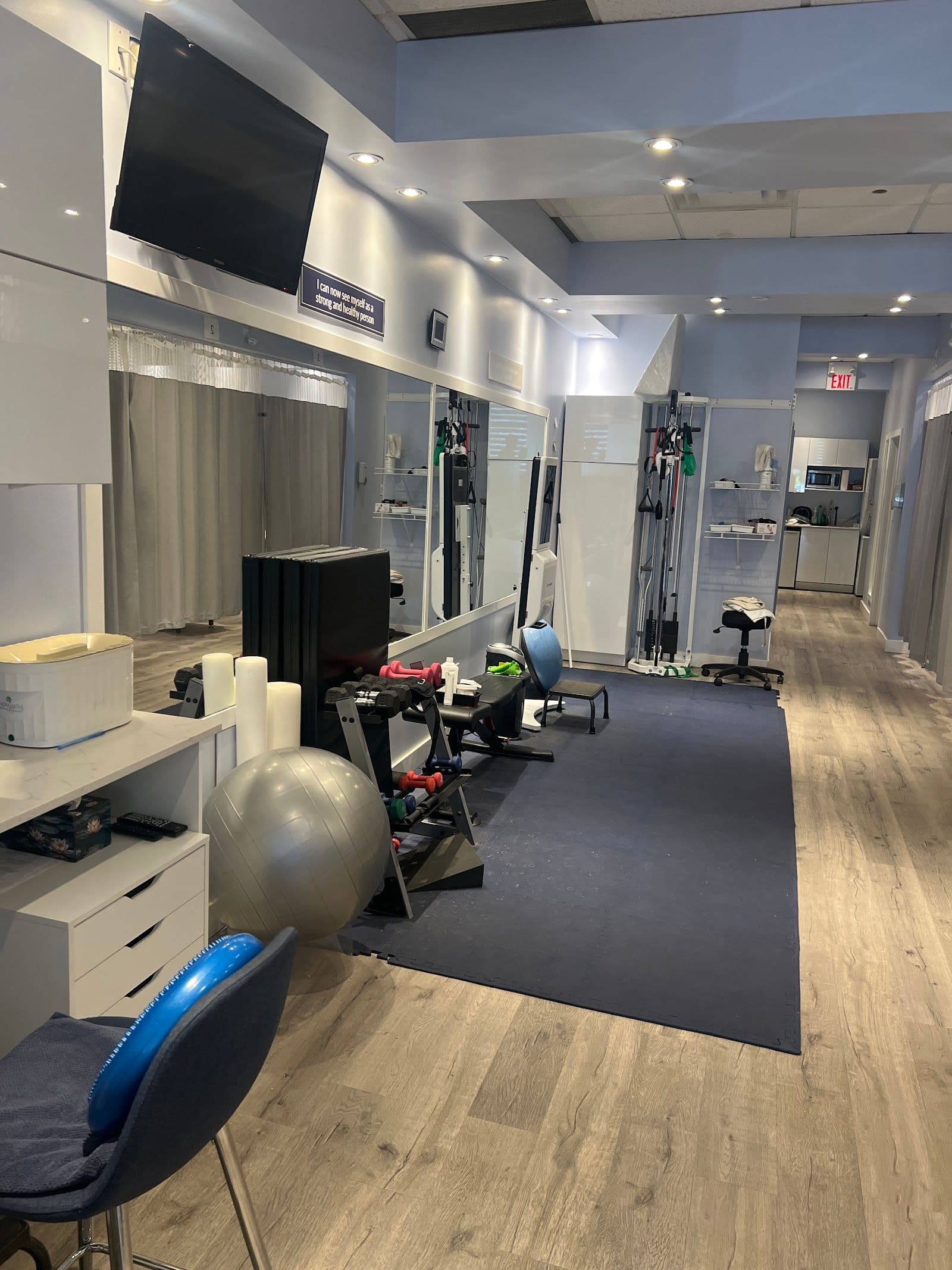 A physiotherapy clinic front desk team reviewing patient feedback and Google reviews together on a tablet in a bright treatment area