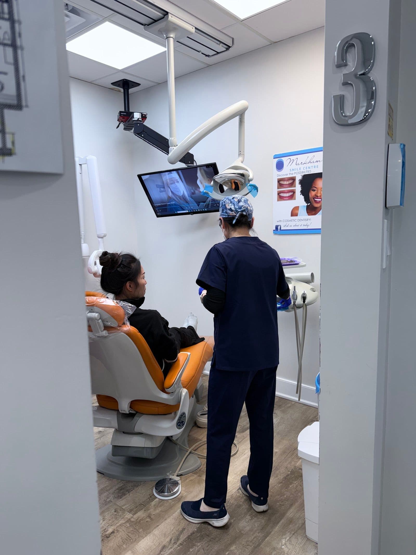 A dental clinic front desk team reviewing patient feedback together on a tablet in a bright, modern reception area