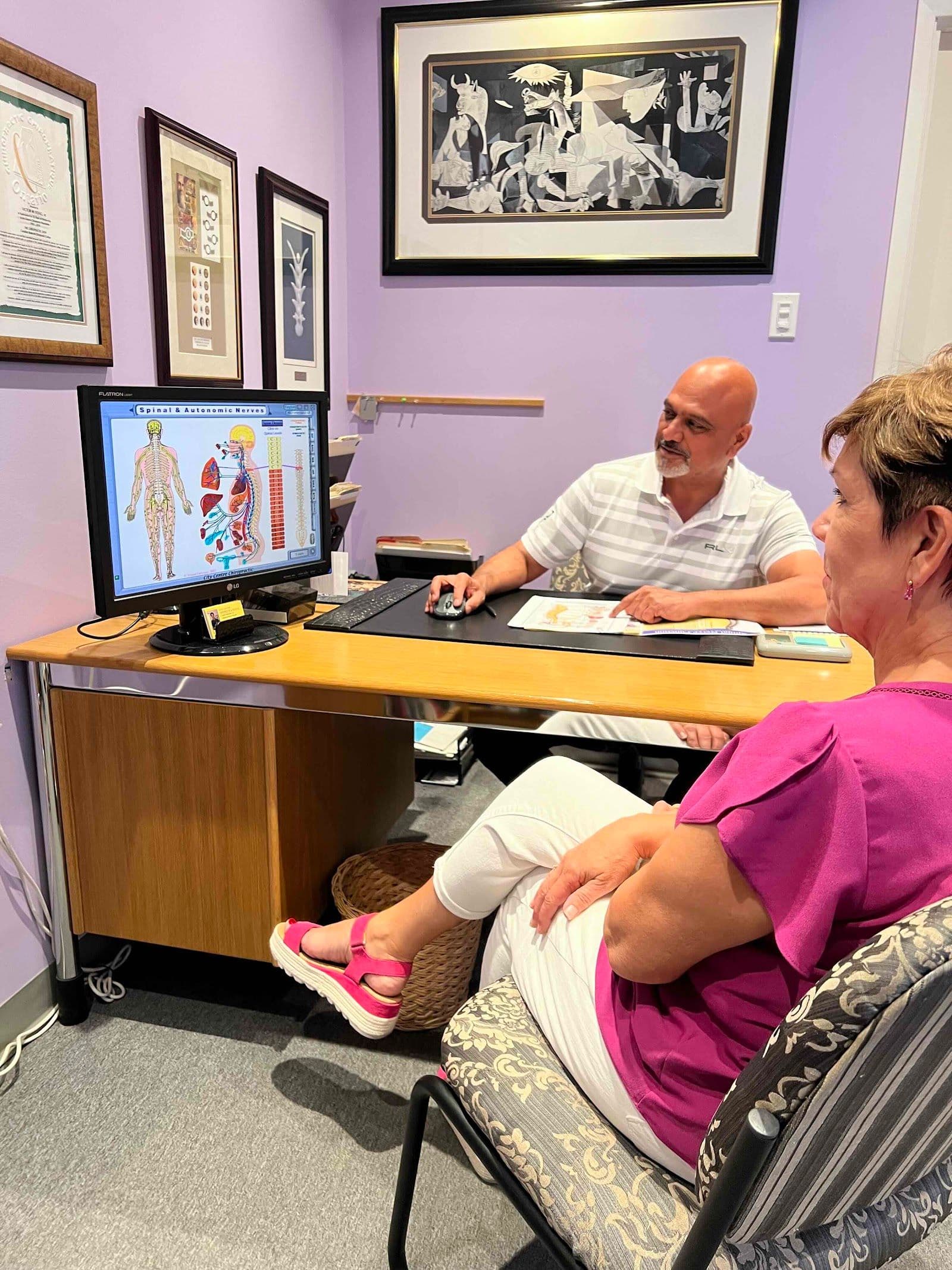 Chiropractic clinic front desk team reviewing patient feedback together on a tablet at the reception area
