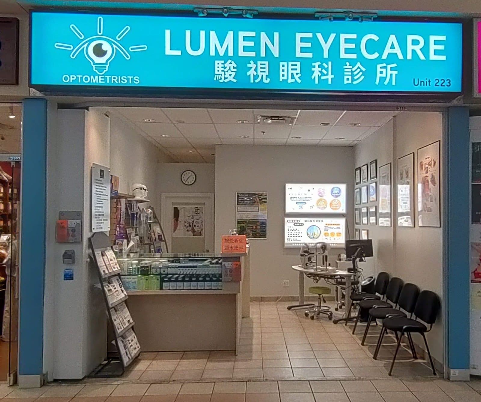 Optometry clinic team reviewing patient feedback together at the front desk, with a monitor displaying Google review summaries