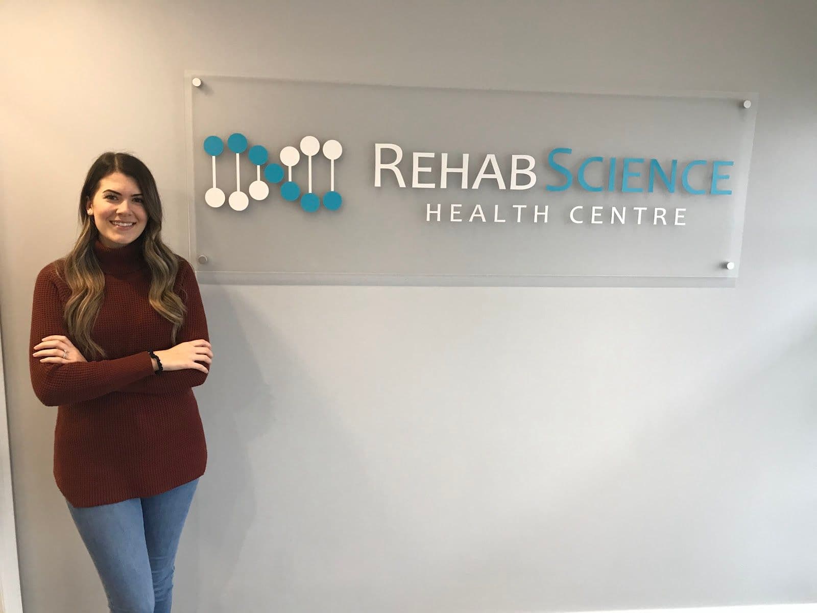 Rehab Science Health Centre clinic team reviewing patient feedback together at the front desk, with a tablet showing Google review summaries
