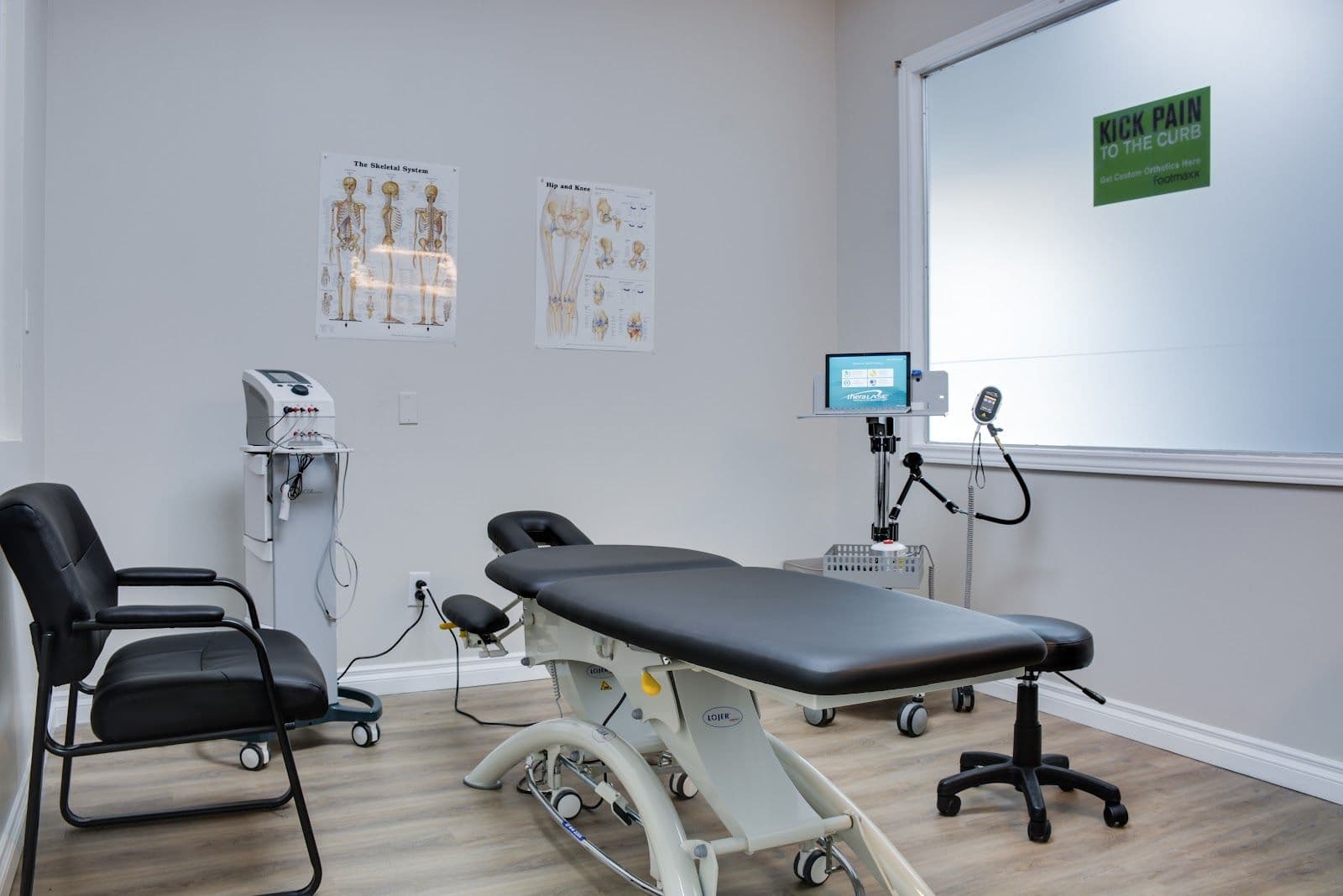 Physiotherapy clinic front desk staff and therapist reviewing patient feedback together on a tablet in a bright treatment area