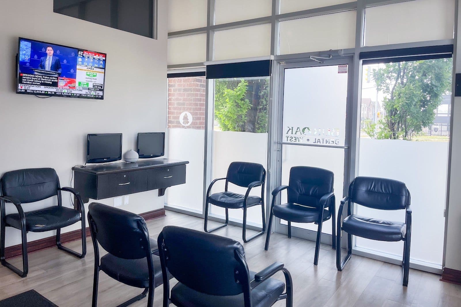 Dental clinic front desk team reviewing patient feedback together on a tablet in a bright, modern reception area