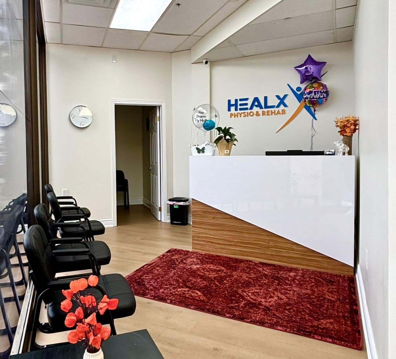A physiotherapy clinic team reviewing patient feedback together at the front desk, with a tablet displaying Google reviews in a clean, welcoming reception area