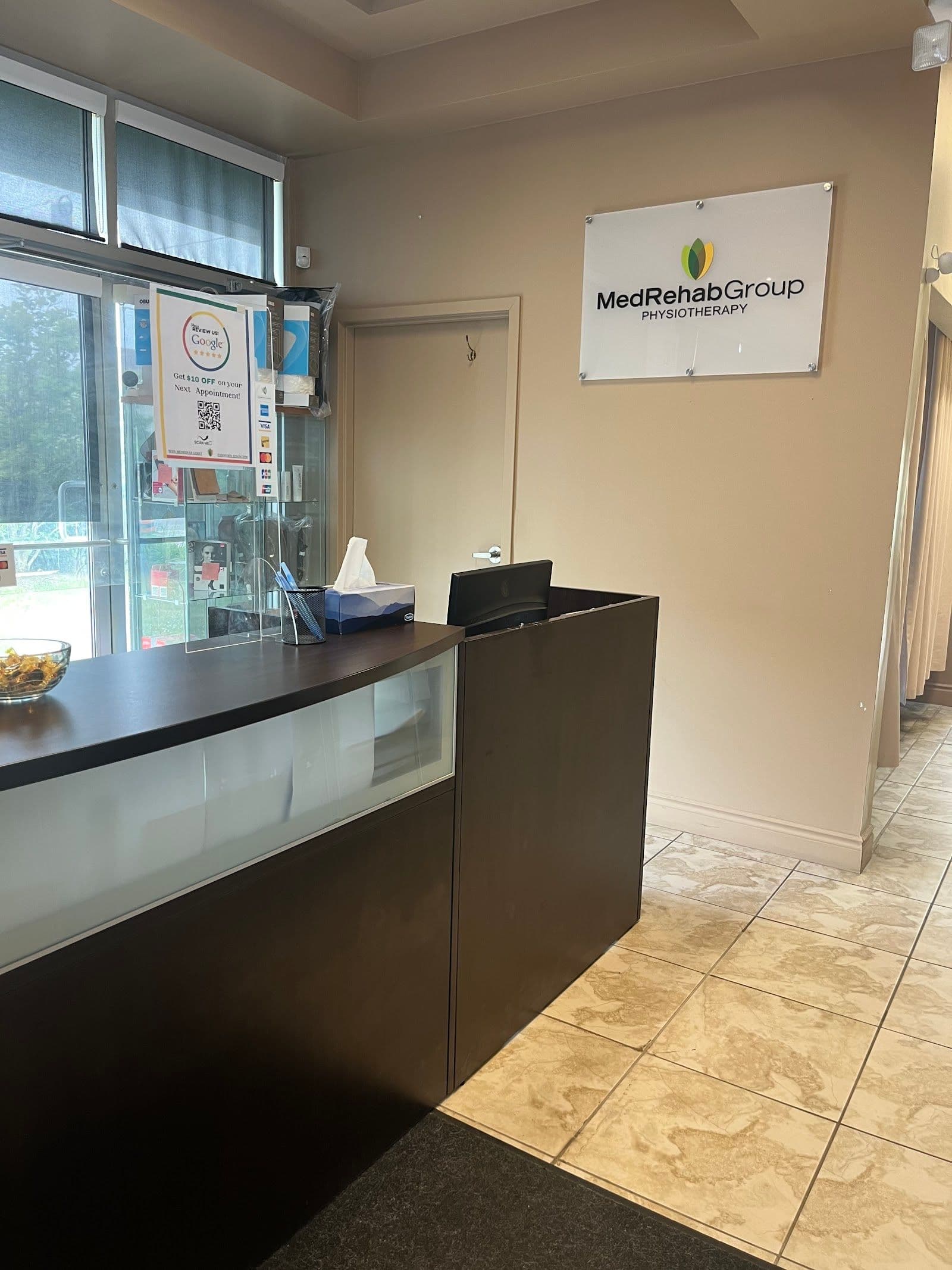 A physiotherapy clinic team reviewing patient feedback together at the front desk, with a tablet displaying Google review summaries