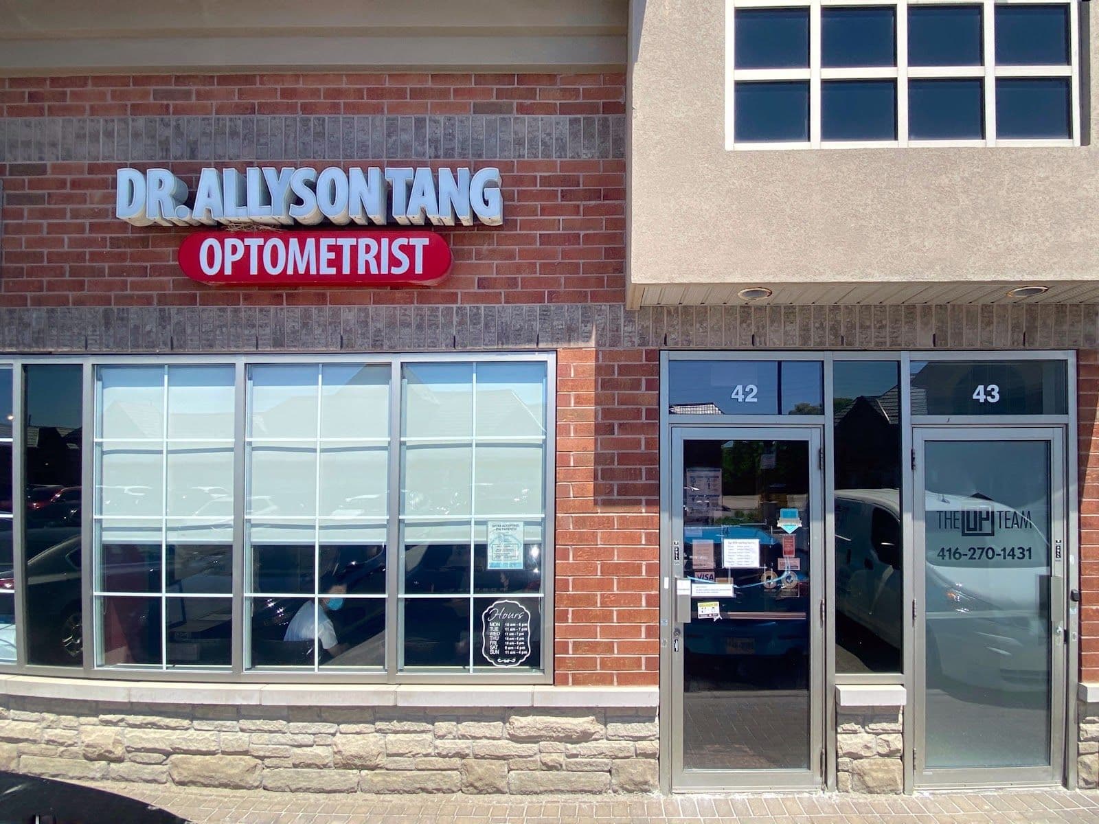 Optometry clinic team reviewing patient feedback together at the front desk, smiling and looking at a tablet in a bright, welcoming reception area