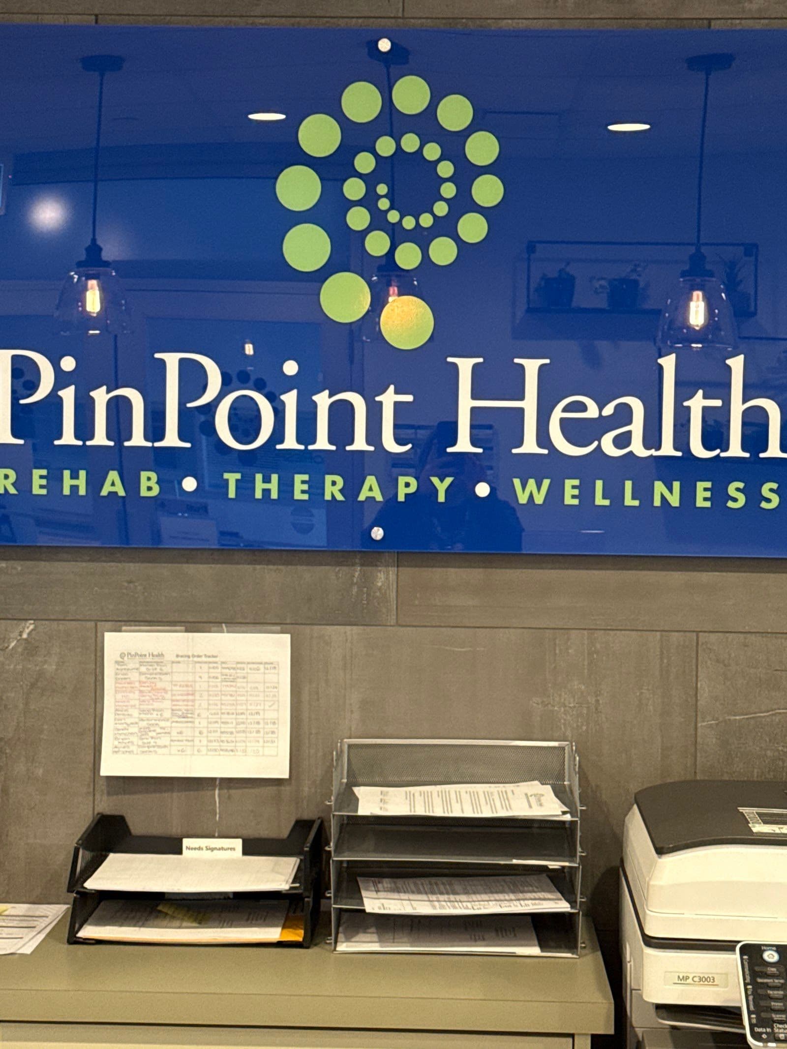 A clinic team member and front desk lead reviewing patient feedback together on a tablet at the PinPoint Health Markham reception area