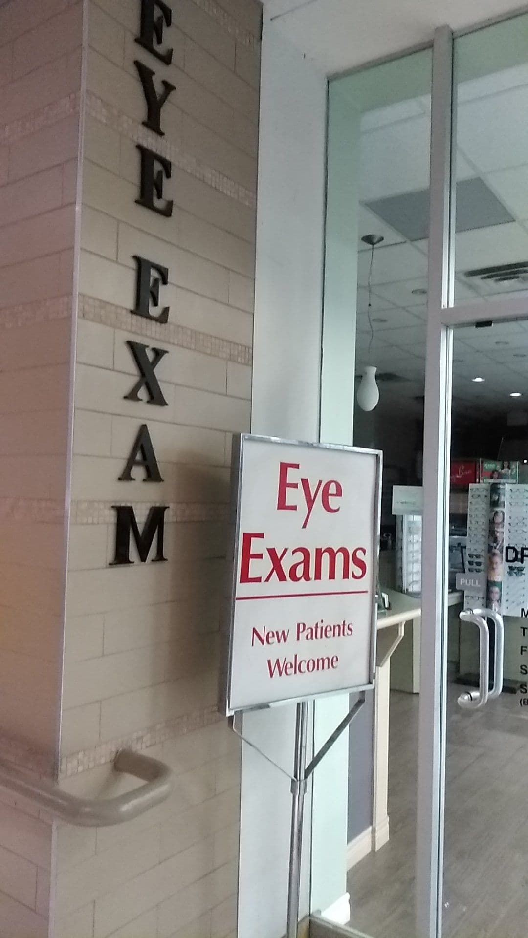 Optometry clinic team reviewing patient feedback together at the front desk, with an eye chart visible in the background