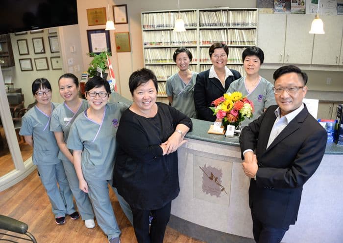 Dental clinic front desk team reviewing patient feedback and Google reviews together on a tablet at the reception counter