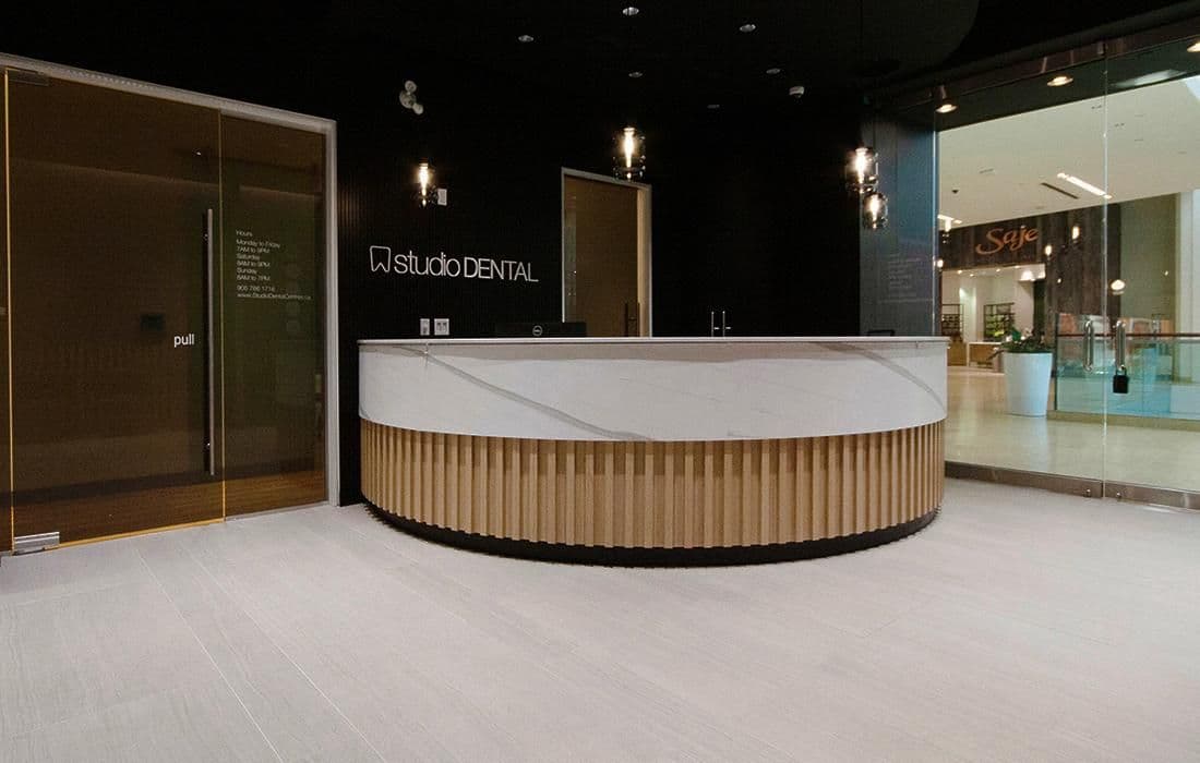 A dental clinic front desk team reviewing patient feedback together on a tablet in a clean, modern reception area