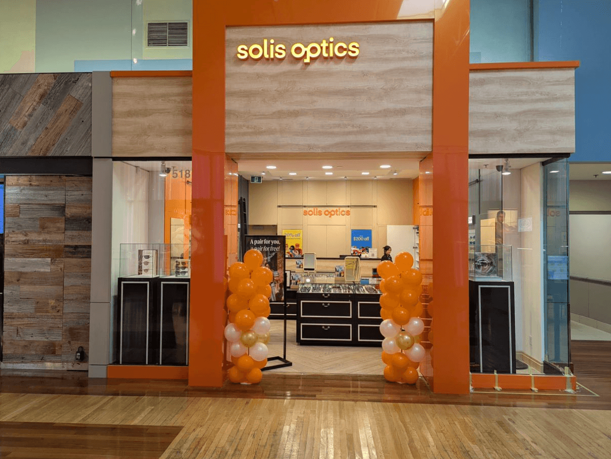 Optometry clinic team reviewing patient feedback together at the front desk near a display of eyewear frames