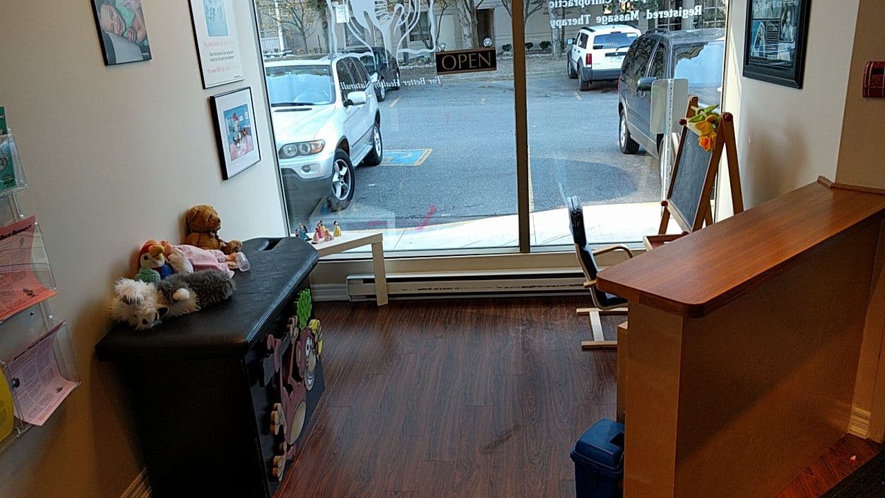 Chiropractic clinic front desk team reviewing patient feedback together on a tablet in a bright reception area