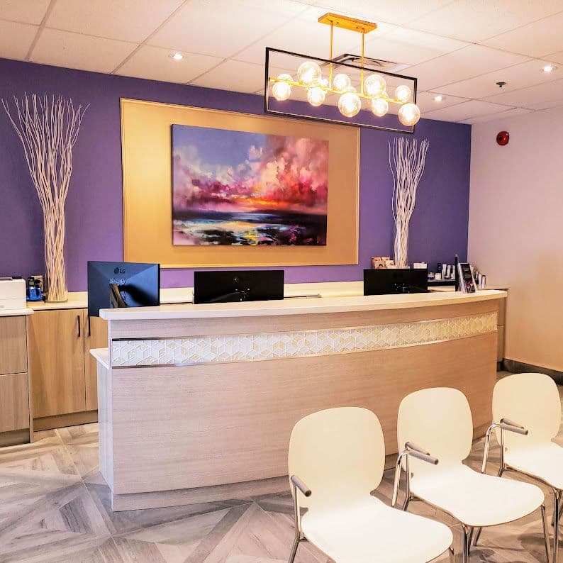 Aesthetic clinic team reviewing patient feedback and Google reviews together at the front desk of a medical aesthetic practice