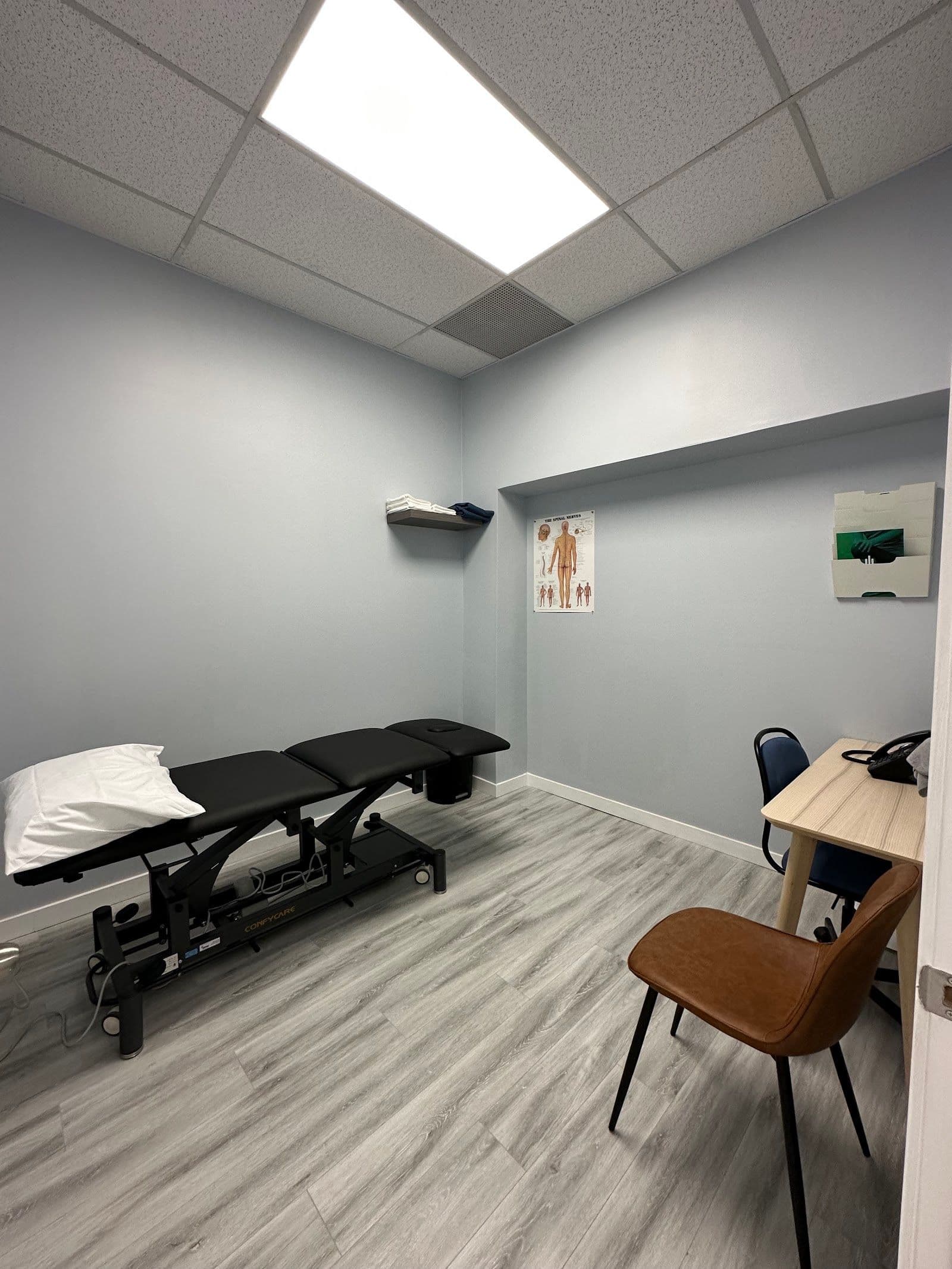 A physiotherapy clinic team member reviewing patient feedback on a tablet at the front desk of a bright, welcoming treatment facility