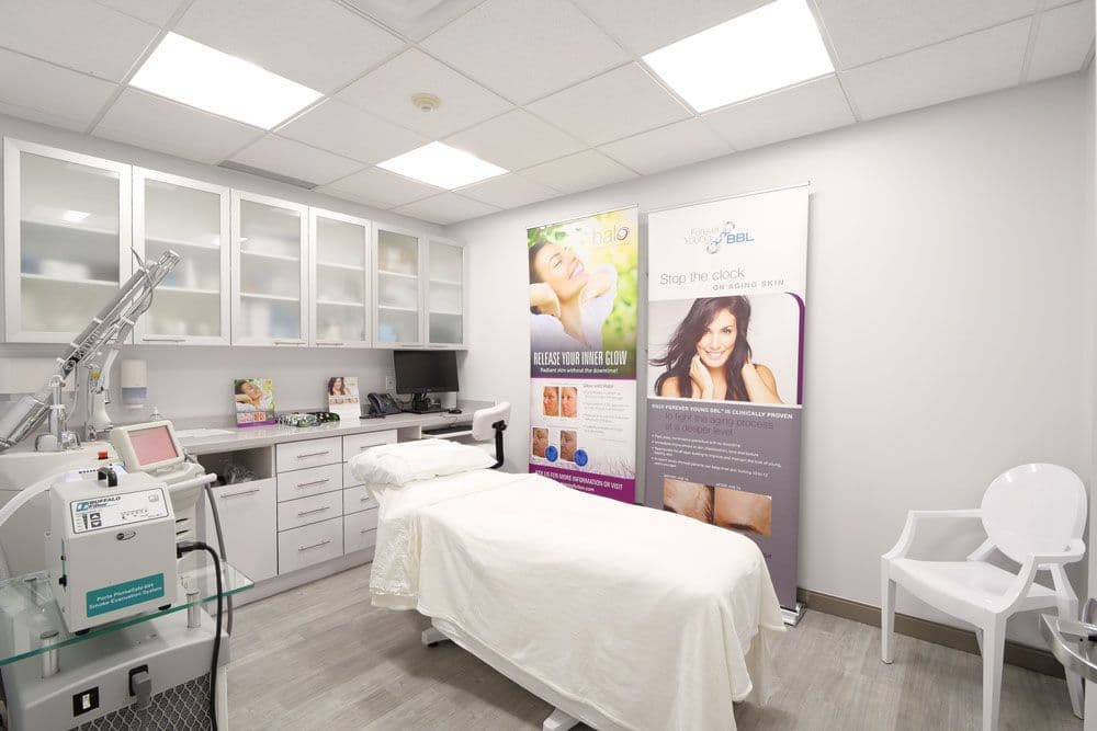 A clinic team member and practice manager reviewing patient feedback together at the front desk of a dermatology and cosmetic centre