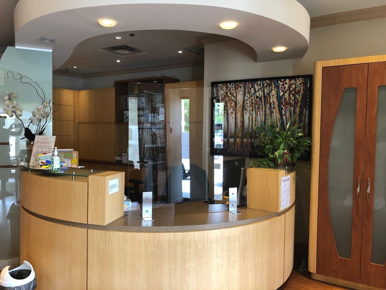 A dental clinic front desk team reviewing patient feedback together on a tablet at the reception area of Lorne Park Dentistry